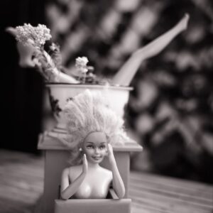 Figura decorativa hecha con una muñeca Barbie y un molinillo vintage pintado de rosa, con flores y brazos en alto - arte friki y original