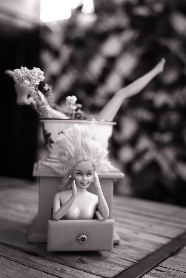 Figura decorativa hecha con una muñeca Barbie y un molinillo vintage pintado de rosa, con flores y brazos en alto - arte friki y original