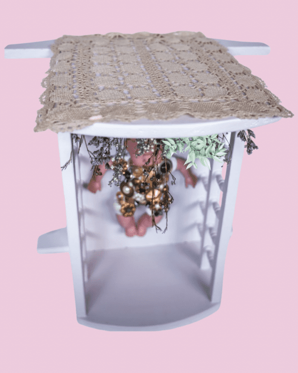 Cuna bebé rosa hielo reconvertida en mesilla con muñeco vintage y flores silvestres