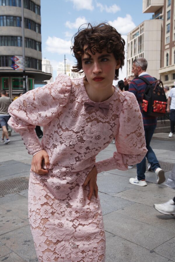 Modelo con vestido largo de encaje rosa, mangas abullonadas y detalles en vichy frente a Cines Callao en madrid