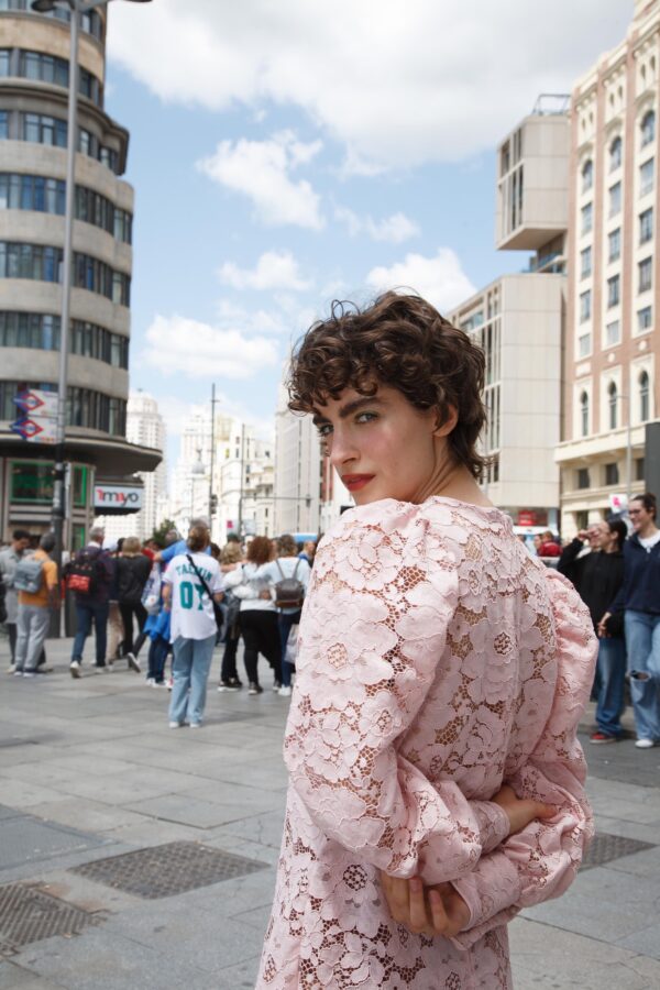 Modelo con vestido largo de encaje rosa, mangas abullonadas y detalles en vichy frente a Cines Callao en Madrid