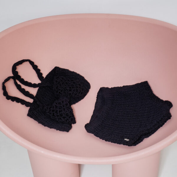 Conjunto de top y culote de punto negro sobre silla rosa con gran lazo