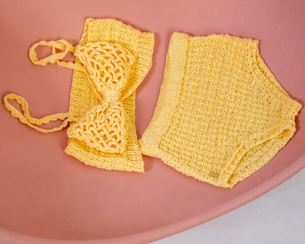 Conjunto de top y culote de punto amarillo sobre silla rosa con gran lazo