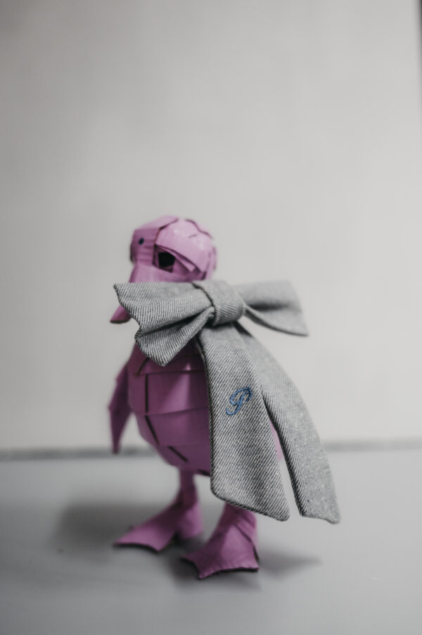 Escultura de cartón en forma de pato rosa con lazo en denim