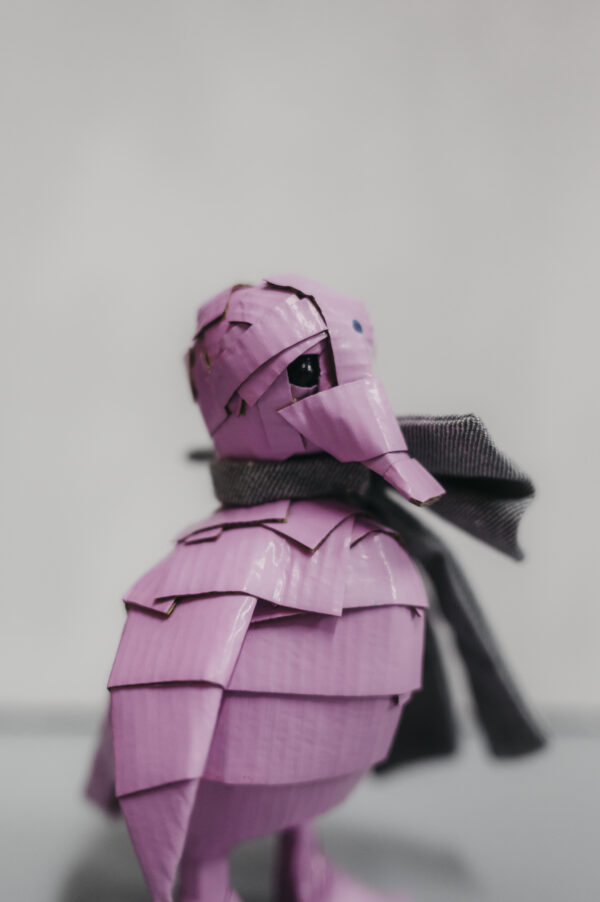 Escultura de cartón en forma de pato rosa con lazo en denim