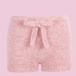 Mini short de mujer rosa tejido a mano en punto de lana y mohair con cintura elástica y lazada frontal en fondo rosa